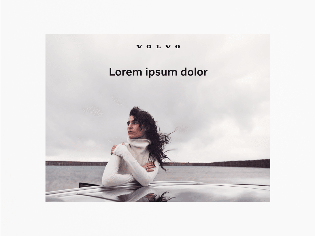 Image of a woman leaning on the roof of a car, waterline in the background and sky above. The Volvo Cars word mark is positioned top centre, set in black. Below that there is a black title that reads 'Lorem ipsum dolor'. The point of this visual is to explain that if an image is generally light, then apply black text and black logo marks. Conversely, if an image is dark in nature, then apply white text and white logo marks. This is good practice as it ensure legibility.